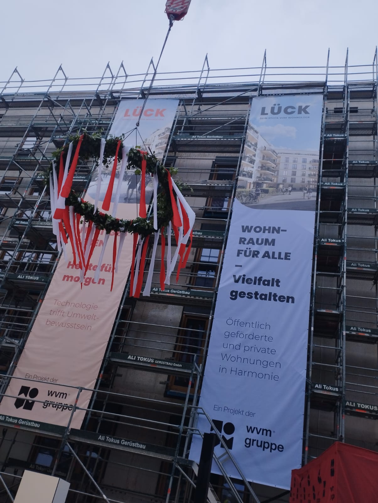 new building complex with banner and green, celebrating topping-out ceremony 