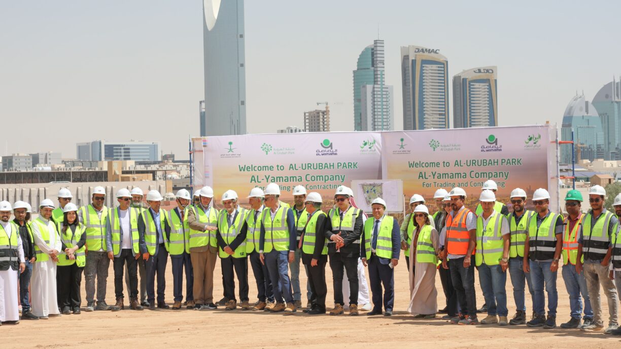 Mixed group with helmets on a construction site with Riyadh skyline in he background