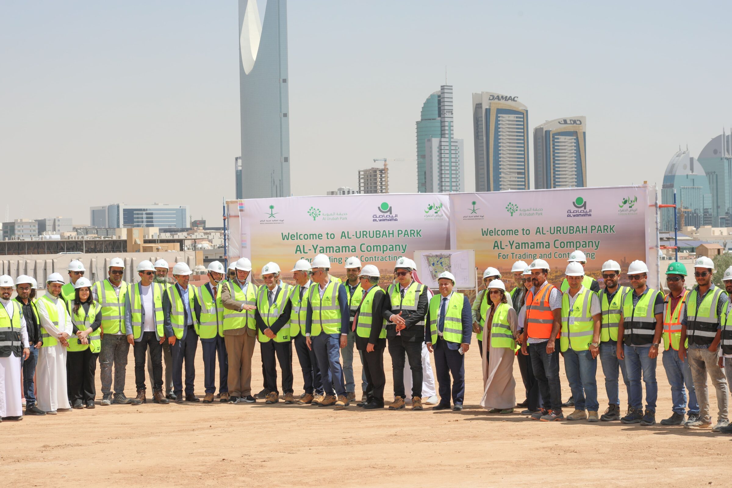 Mixed group with helmets on a construction site with Riyadh skyline in he background