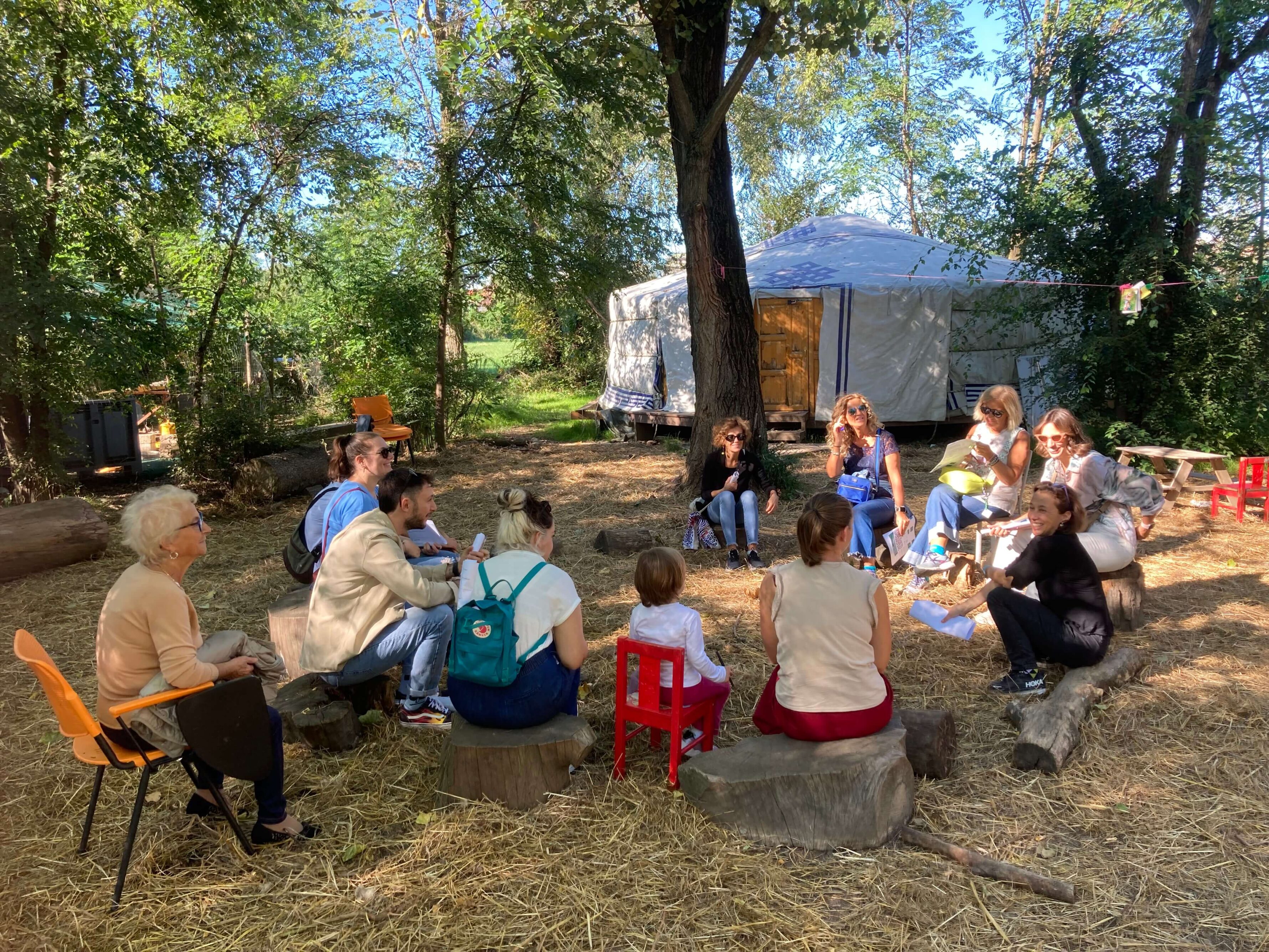 A group of doverse people sitting in circle, listening attentively in a rural context