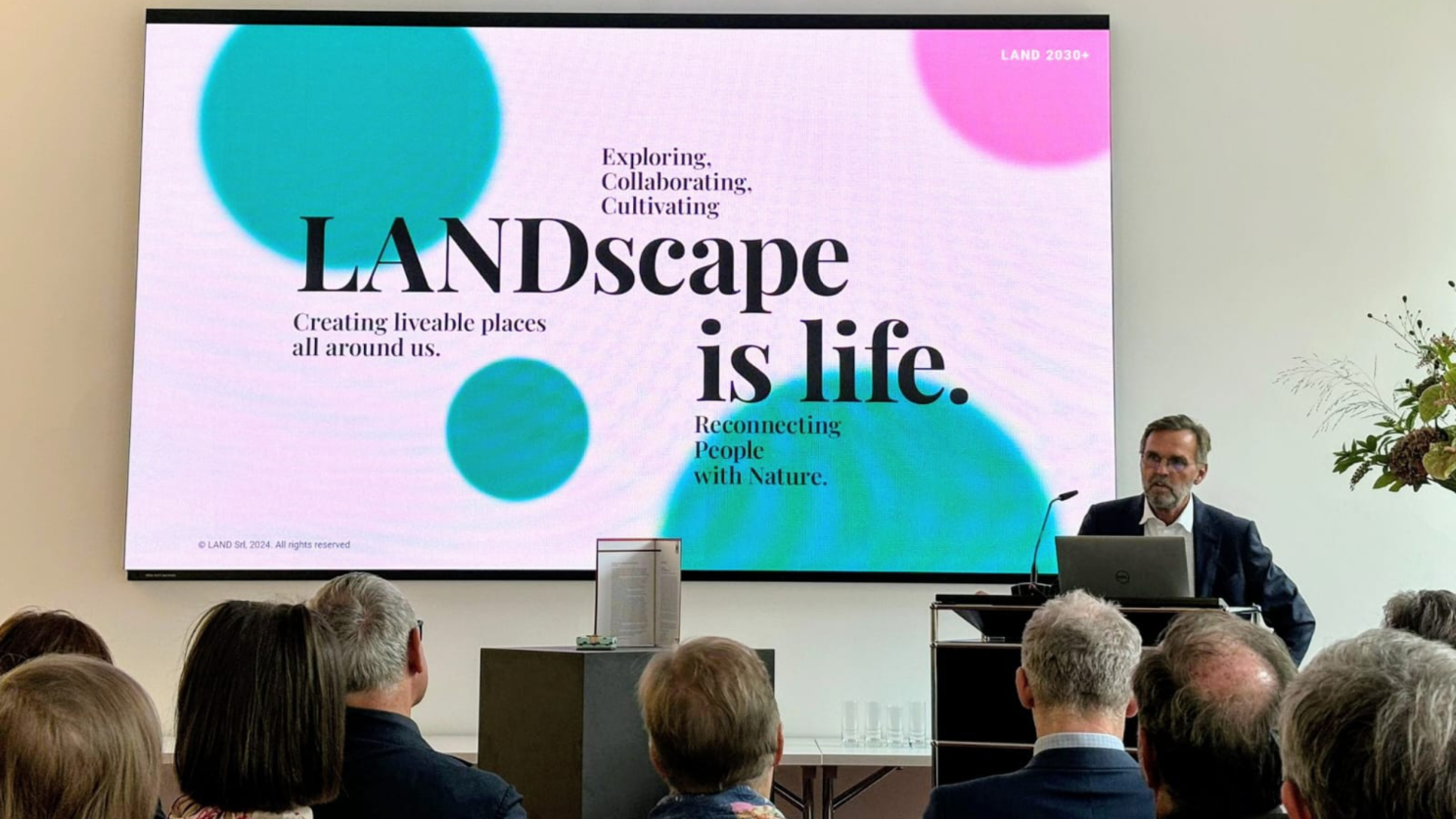 A man presenting a slide with title Landscape is life