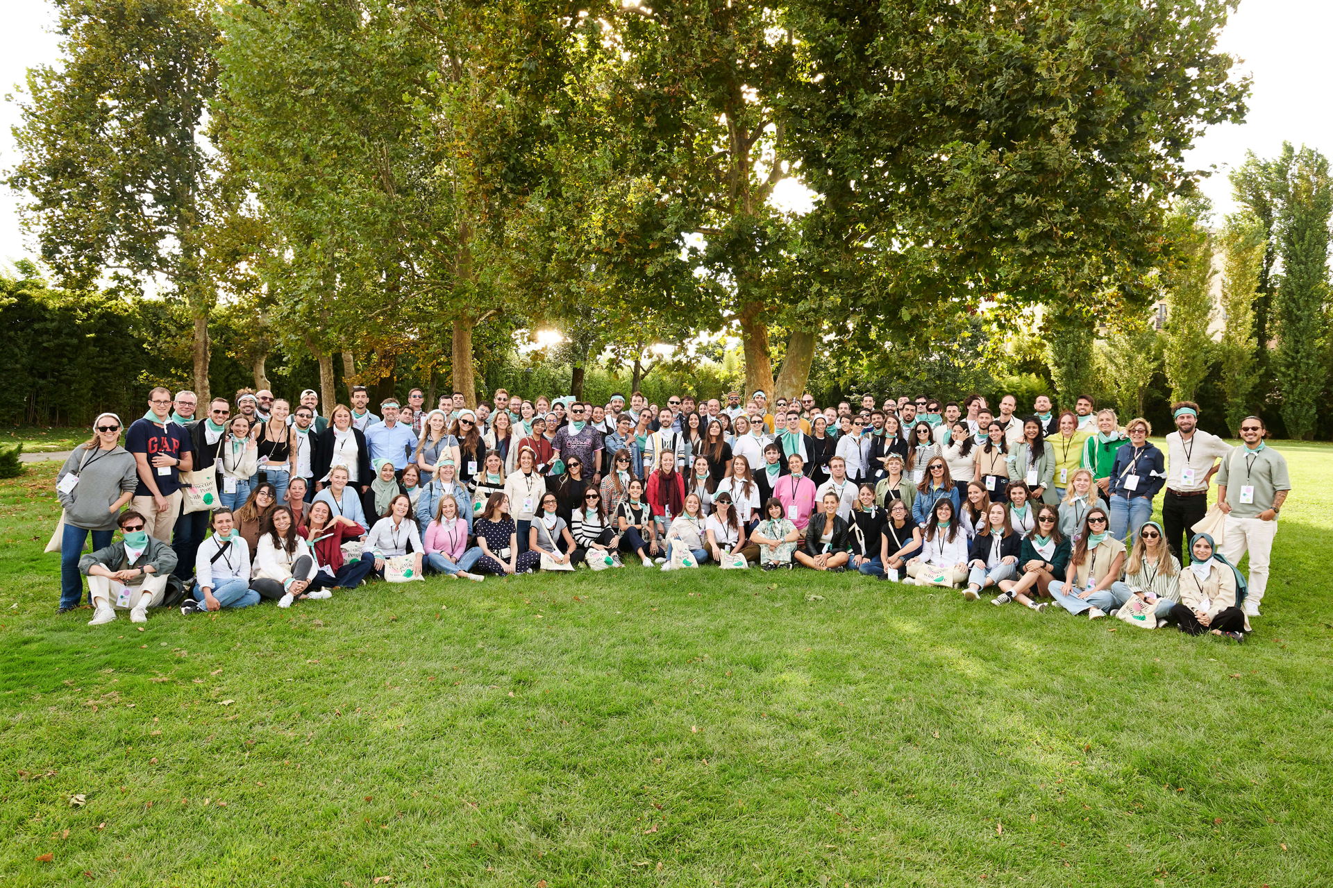 100 people for a group image on a green lawn and trees in background