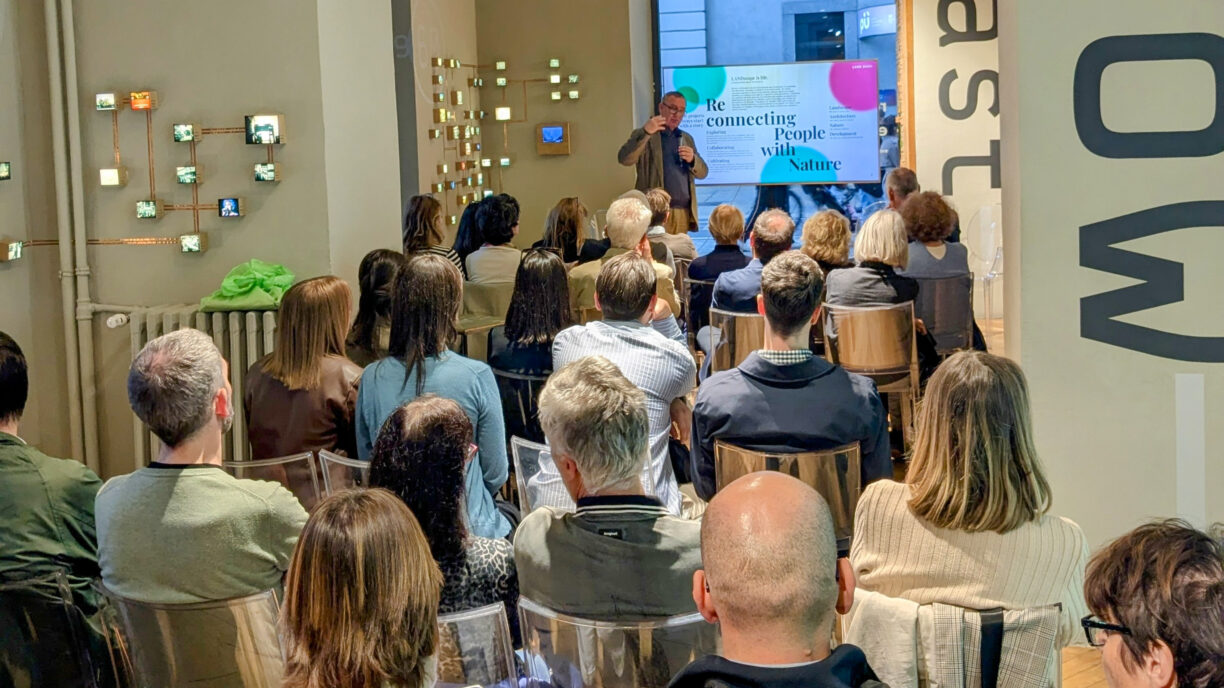 People sitting in a room with a man presenting slides