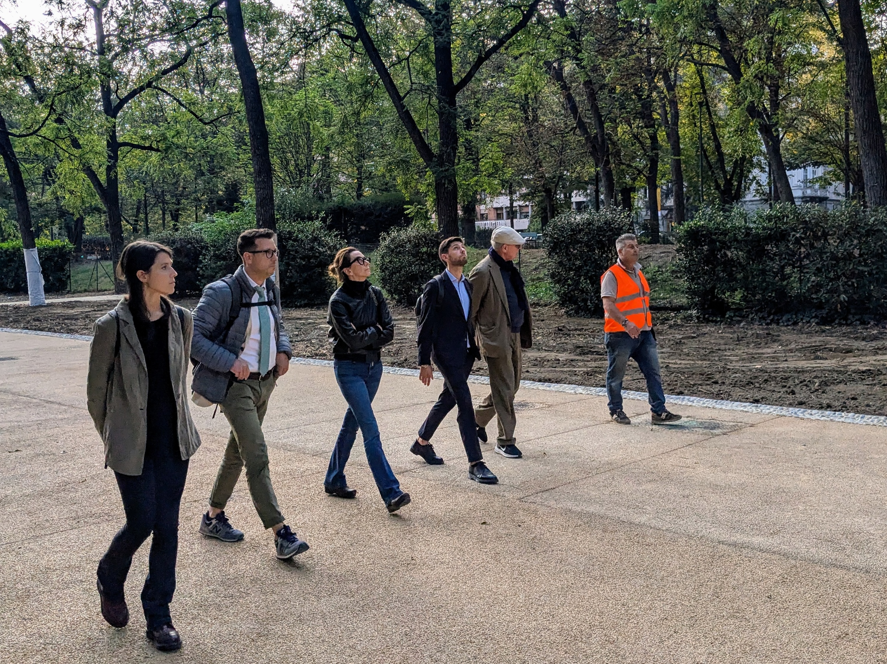 Six people of different ages walking on an alleyway in a park